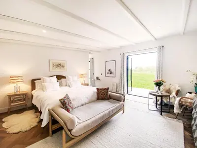 a bedroom with a bed and a couch and a window at Little Owl by The Suffolk Cottage Collection in Aldeburgh