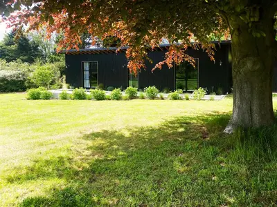 a black building with a tree in the yard at Little Owl by The Suffolk Cottage Collection in Aldeburgh