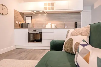 a living room with a green couch and a kitchen at Guildhall Street Apartment, Bury St Edmunds in Bury Saint Edmunds