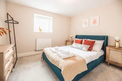 a bedroom with a blue bed and a dresser at Guildhall Street Apartment, Bury St Edmunds in Bury Saint Edmunds