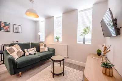 a living room with a green couch and a table at Guildhall Street Apartment, Bury St Edmunds in Bury Saint Edmunds