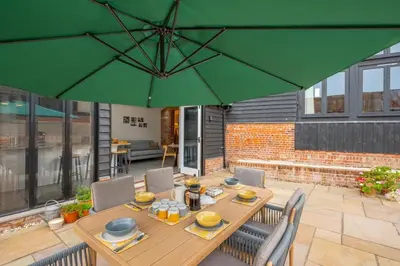 a wooden table with chairs and a green umbrella at 3 Bed in Kersey oc-tcbk in Kersey
