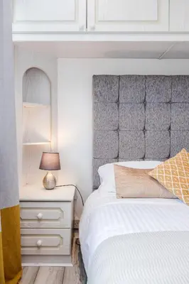 a bedroom with a bed and a dresser with a mirror at Bright and spacious home with free parking and garden in Mountnessing