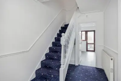a white staircase with blue carpeted floors and white walls at Bright and spacious home with free parking and garden in Mountnessing