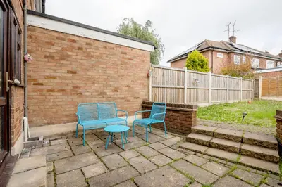 two blue chairs and a table in a backyard at Bright and spacious home with free parking and garden in Mountnessing