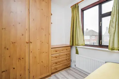 a bedroom with wooden cabinets and a window at Bright and spacious home with free parking and garden in Mountnessing