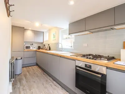 a kitchen with white cabinets and a stove top oven at Wherry Cottage in Manningtree