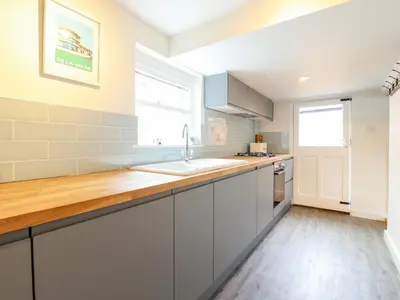 a kitchen with white cabinets and a sink at Wherry Cottage in Manningtree