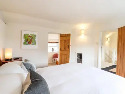 a bedroom with a white bed and a fireplace at Wherry Cottage in Manningtree