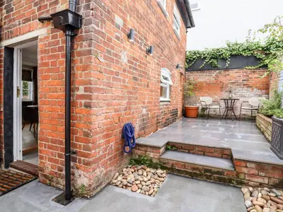 a brick building with a courtyard with a patio at Wherry Cottage in Manningtree