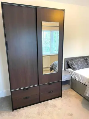 a large wooden cabinet with a mirror in a bedroom at Fantastic Holiday Home in Laindon