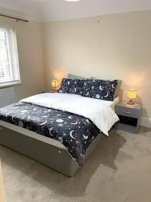 a bedroom with a bed with a black and white comforter at Fantastic Holiday Home in Laindon