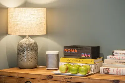 a lamp sitting on a table with books and apples at Tipple Cottage in Peasenhall