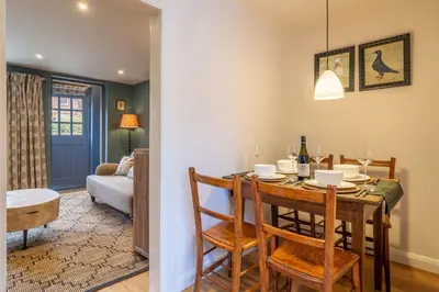 a dining room and living room with a table and chairs at Tipple Cottage in Peasenhall