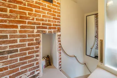 a brick wall in a hallway with a mirror at Tipple Cottage in Peasenhall