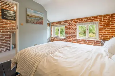 a large bed in a room with a brick wall at Tipple Cottage in Peasenhall