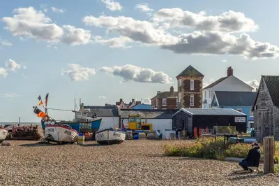 a person sitting on the beach next to a boat at Tipple Cottage in Peasenhall