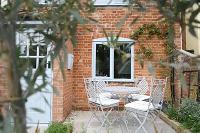 a table and chairs in front of a brick wall at Tipple Cottage in Peasenhall