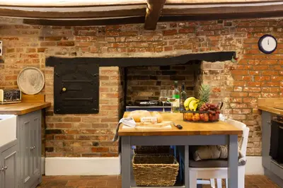 a kitchen with a brick wall and a table with fruit at Vine Cottage in Walsham le Willows