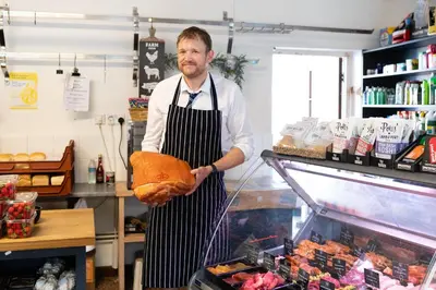 a man holding a loaf of bread in a kitchen at Vine Cottage in Walsham le Willows