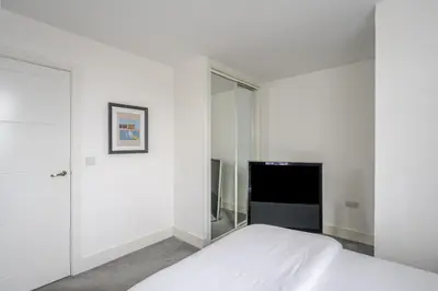 a white bedroom with a bed and a tv at Luxurious 2 Bedroom Apartment with Free Parking, Sky TV, Sports, Movies & Netflix in Chelmsford