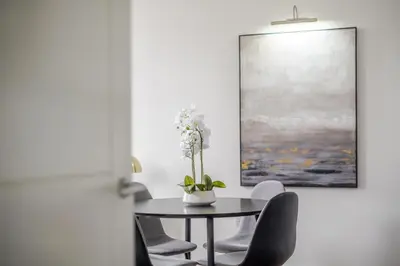 a dining room table with chairs and a vase with flowers on it at Luxurious 2 Bedroom Apartment with Free Parking, Sky TV, Sports, Movies & Netflix in Chelmsford