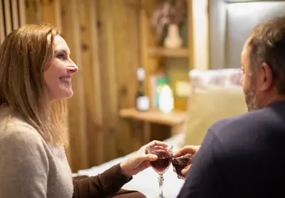 a woman and man holding glasses of wine at City to Country Retreat Luxury Lodges with Hot Tub, BBQ, Fire Pit in Toppesfield