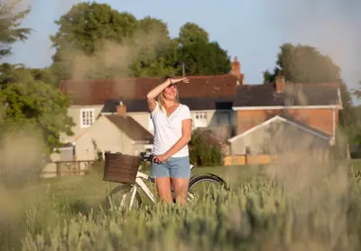 a woman standing next to a bike in a field at City to Country Retreat Luxury Lodges with Hot Tub, BBQ, Fire Pit in Toppesfield