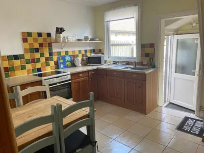 a kitchen with wooden cabinets and a table with a microwave at 160 Exning Road in Newmarket