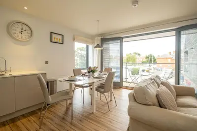 a kitchen and dining room with a table and a clock at 2 King Georges - Aldeburgh Coastal Cottages in Aldeburgh
