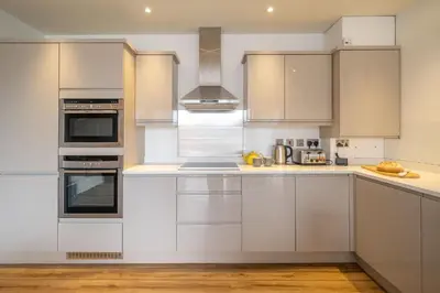 a kitchen with white cabinets and stainless steel appliances at 2 King Georges - Aldeburgh Coastal Cottages in Aldeburgh