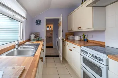a kitchen with white cabinets and a sink at 40 Buller Road - Aldeburgh Coastal Cottages in Leiston