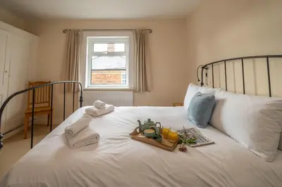 a white bed with a tray of food on it at 40 Buller Road - Aldeburgh Coastal Cottages in Leiston