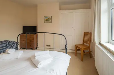 a bedroom with a bed and a chair and a window at 40 Buller Road - Aldeburgh Coastal Cottages in Leiston