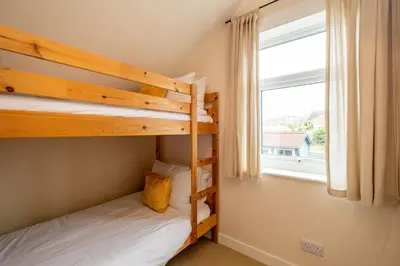 two bunk beds in a room with a window at 40 Buller Road - Aldeburgh Coastal Cottages in Leiston