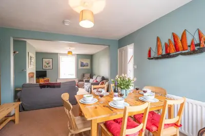 a dining room and living room with a table and chairs at 40 Buller Road - Aldeburgh Coastal Cottages in Leiston