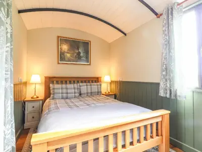 a bedroom with a bed and a window at The Brake Wagon at High Barn Heritage in Halstead