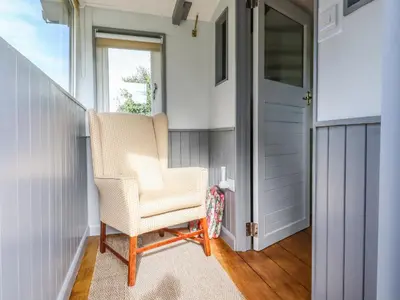 a hallway with a chair and a door at The Brake Wagon at High Barn Heritage in Halstead