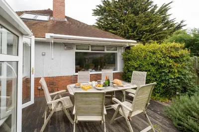 a patio with a table and chairs on a deck at Pinewood - Aldeburgh Coastal Cottages in Aldeburgh