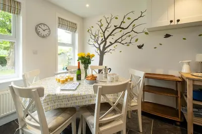 a dining room with a table and a tree on the wall at Pinewood - Aldeburgh Coastal Cottages in Aldeburgh
