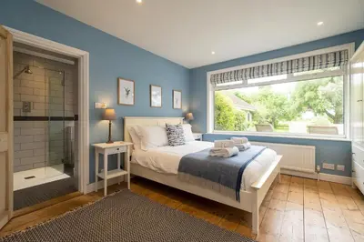 a bedroom with a bed and a shower and a window at Pinewood - Aldeburgh Coastal Cottages in Aldeburgh