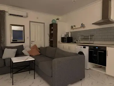 a living room with a couch and a kitchen at Fully Detached Studio Annexe with King Bed for 2 & Sofa Bed for 2 in Cambourne