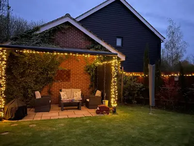 a backyard with a pergola with lights on it at Fully Detached Studio Annexe with King Bed for 2 & Sofa Bed for 2 in Cambourne