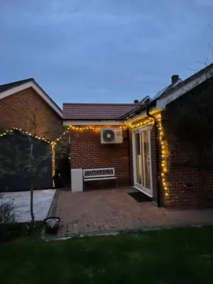 a house with christmas lights on the side of it at Fully Detached Studio Annexe with King Bed for 2 & Sofa Bed for 2 in Cambourne