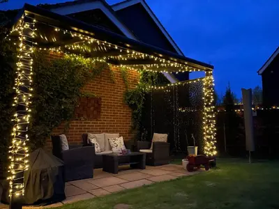 a pergola with lights in a backyard at night at Fully Detached Studio Annexe with King Bed for 2 & Sofa Bed for 2 in Cambourne
