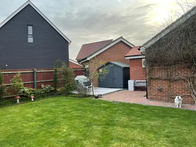 a house with a dog standing in a yard at Fully Detached Studio Annexe with King Bed for 2 & Sofa Bed for 2 in Cambourne