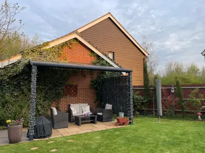 a patio with two chairs and a table in a yard at Fully Detached Studio Annexe with King Bed for 2 & Sofa Bed for 2 in Cambourne
