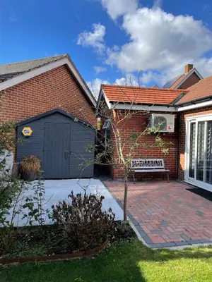 a brick house with a garage and a bench at Fully Detached Studio Annexe with King Bed for 2 & Sofa Bed for 2 in Cambourne