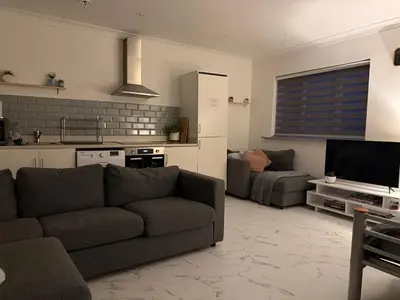a living room with a couch and a kitchen at Fully Detached Studio Annexe with King Bed for 2 & Sofa Bed for 2 in Cambourne