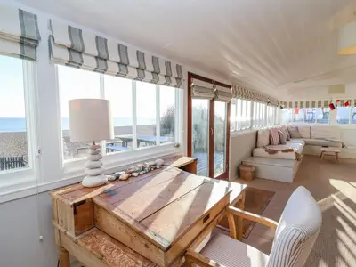 a living room with a table and some windows at Valetta, Thorpeness in Thorpeness